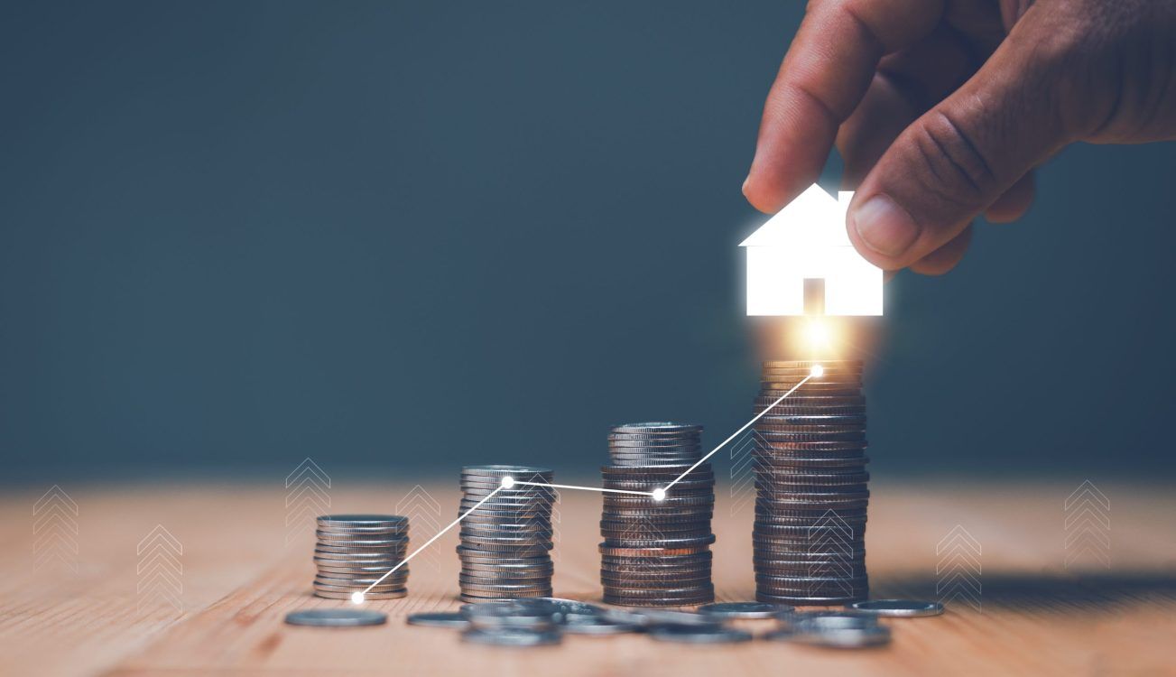 Investment for real estate concept, Businessman's hand putting house icon on top of coins stack and progressing graph, Savings money for buy house, budgeting, investment for the future.